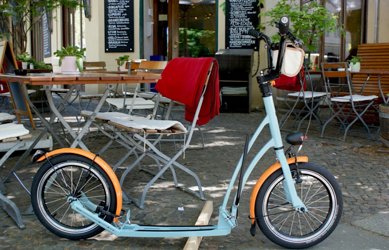 Tretroller MIBO MASTR im Retro-Style vor dem Eingang zum Kaffeehaus
