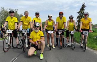 Acht TretrollerfahrerInnen in gelben Tikos vor dem Start.